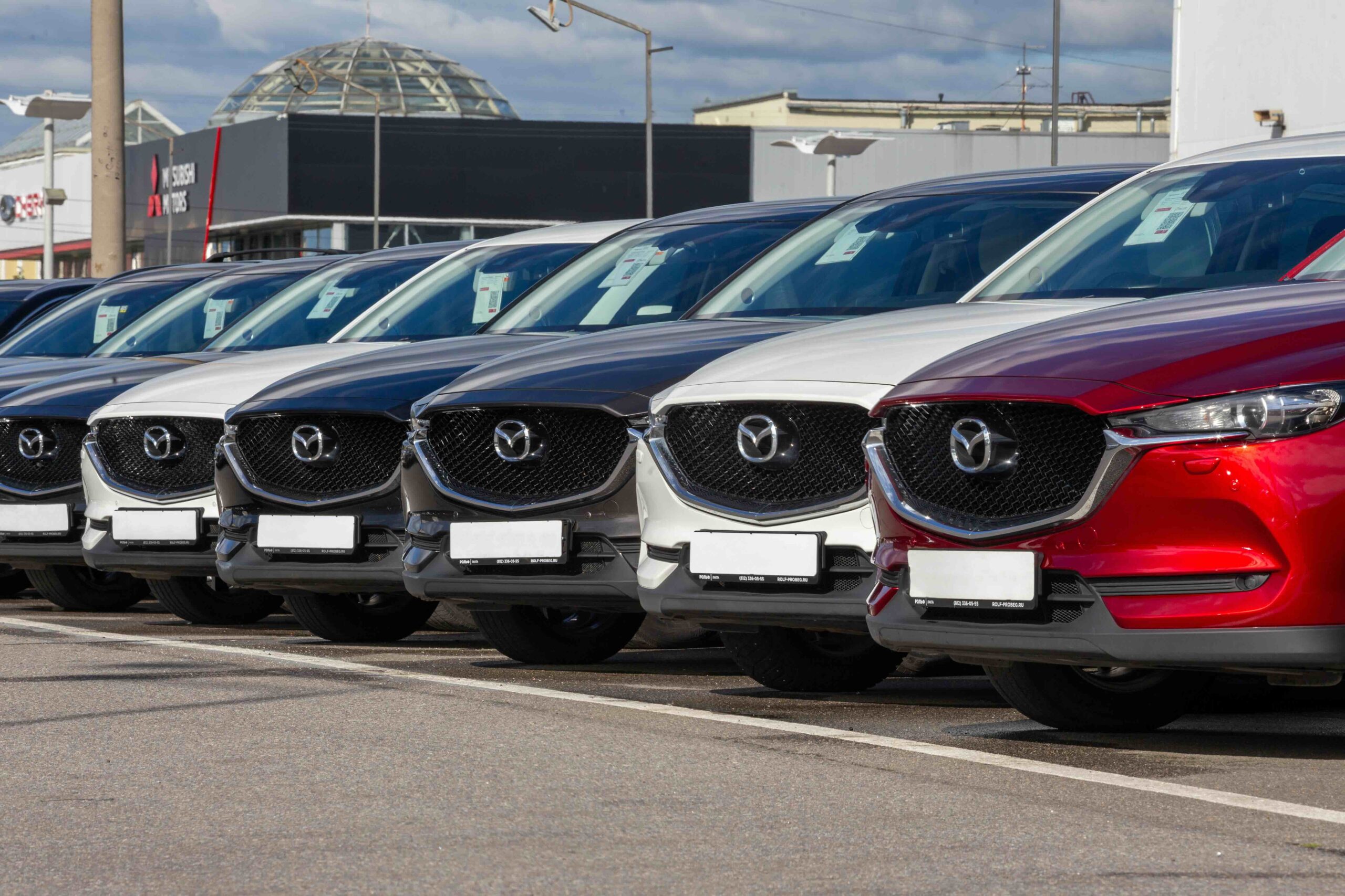 Side view of a new cars Mazda CX-5 with showroom displaying logo in the background. Mazda CX-5, modern crossover made in Japan. Japan car. Cars for sale.